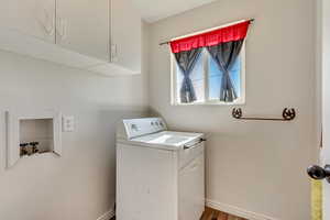 Clothes washing area with cabinets, wood-type flooring, and washer / clothes dryer