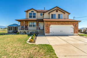 View of front of home with covered porch, a garage, and a front yard