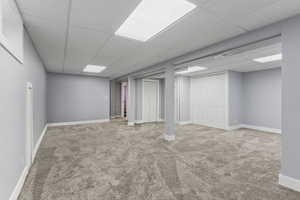 Basement with carpet flooring and a drop ceiling