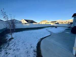 Yard covered in snow featuring a mountain view