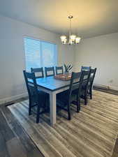 Dining area with dark wood-type flooring and a notable chandelier