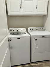 Laundry room with washer and dryer, dark hardwood / wood-style floors, and cabinets