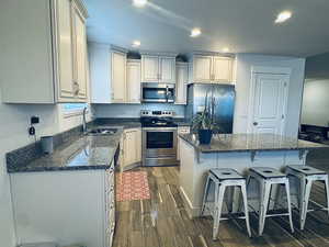 Kitchen with a center island, dark stone counters, sink, appliances with stainless steel finishes, and dark hardwood / wood-style flooring