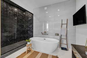 Bathroom featuring tile patterned floors, tile walls, and shower with separate bathtub