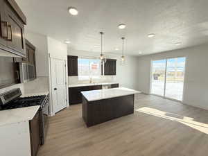 Kitchen featuring appliances with stainless steel finishes, light hardwood / wood-style floors, a kitchen island, and a wealth of natural light