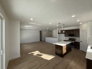 Kitchen with pendant lighting, a center island, dark wood-type flooring, appliances with stainless steel finishes, and tasteful backsplash