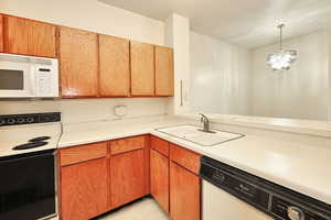 Kitchen featuring a chandelier, white appliances, decorative light fixtures, and sink