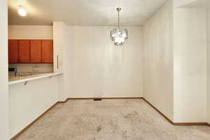 Unfurnished dining area with light colored carpet and a chandelier