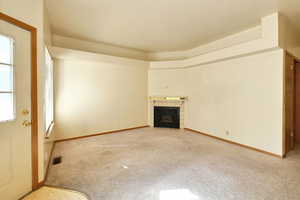 Unfurnished living room featuring carpet flooring and a tiled fireplace