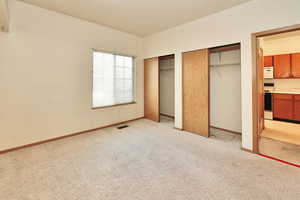 Unfurnished bedroom with light carpet and two closets