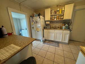 Kitchen with white refrigerator with ice dispenser, light tile patterned floors, white cabinetry, and sink