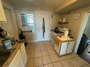 Kitchen featuring white cabinets, white electric range, sink, and light tile patterned floors