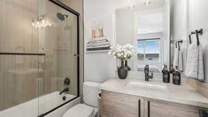 Full bathroom featuring vanity, enclosed tub / shower combo, and toilet