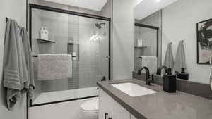 Full bathroom with vanity, toilet, and bath / shower combo with glass door