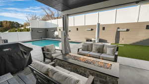 View of pool with a grill, a patio, and an outdoor living space with a fire pit