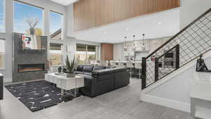 Living room with tile patterned floors, a wealth of natural light, a fireplace, and a high ceiling