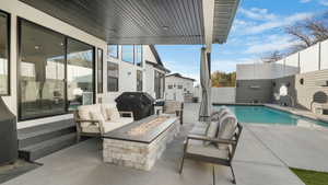 View of swimming pool with a grill, an outdoor living space with a fire pit, and a patio