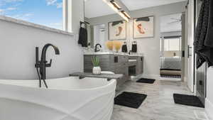 Bathroom with ceiling fan, vanity, and a bath