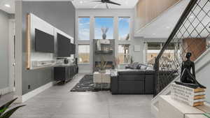 Living room featuring ceiling fan, a large fireplace, and a towering ceiling