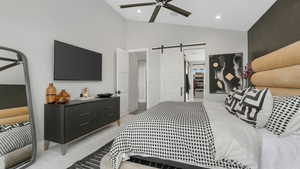 Bedroom with a barn door, ceiling fan, high vaulted ceiling, and light colored carpet