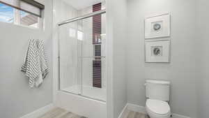 Bathroom with toilet, tile, and bath / shower combo with glass door