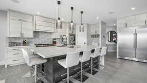 Kitchen with sink, stainless steel appliances, hanging light fixtures, and an island with sink