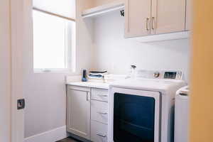 Clothes washing area featuring washing machine and dryer and cabinets