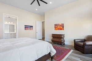 Bedroom featuring wood-type flooring, ensuite bath, and ceiling fan