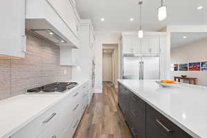 Kitchen with decorative light fixtures, white cabinetry, light hardwood / wood-style flooring, and stainless steel appliances