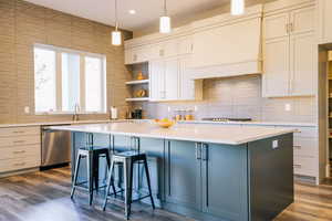 Kitchen with stainless steel appliances, pendant lighting, white cabinetry, dark hardwood / wood-style floors, and a kitchen island