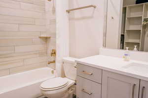 Full bathroom with vanity, tiled shower / bath combo, and toilet