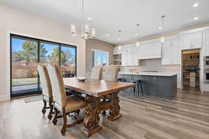 Dining space with light wood-type flooring and an inviting chandelier