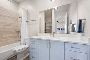 Full bathroom with ceiling fan, hardwood / wood-style floors, toilet, vanity, and shower / tub combo with curtain