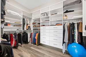 Walk in closet with light hardwood / wood-style floors