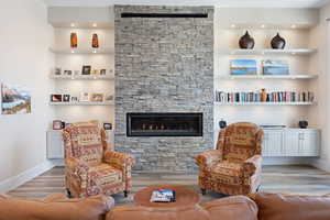 Living room with light hardwood / wood-style flooring and a stone fireplace