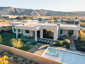 Back of property featuring a mountain view, a patio, and a pool with hot tub