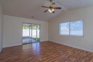 Empty room featuring ceiling fan, lofted ceiling, and dark wood-type flooring