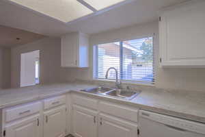 Kitchen featuring kitchen peninsula, white cabinetry, sink, and white dishwasher