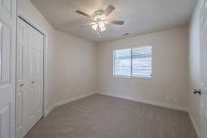 Unfurnished bedroom with ceiling fan, a closet, carpet, and a textured ceiling