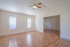 Unfurnished room with ceiling fan, hardwood / wood-style floors, and vaulted ceiling