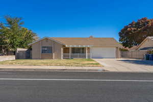 Ranch-style home with a porch, a garage, and a front lawn