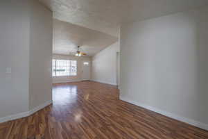 Spare room featuring lofted ceiling, dark hardwood / wood-style flooring, ceiling fan, and a textured ceiling