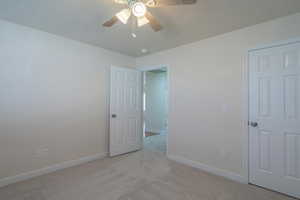 Unfurnished bedroom featuring ceiling fan and light carpet