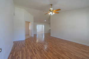 Empty room with dark hardwood / wood-style flooring, high vaulted ceiling, and ceiling fan