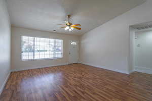 Empty room featuring a textured ceiling, ceiling fan, and dark wood-type flooring