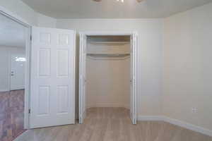 Unfurnished bedroom with light wood-type flooring, a closet, and ceiling fan