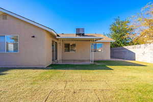 Back of property with a lawn, a patio area, and central AC