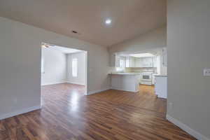 Unfurnished living room featuring lofted ceiling, sink, ceiling fan, and dark hardwood / wood-style floors