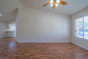 Empty room featuring a textured ceiling, ceiling fan, sink, wood-type flooring, and lofted ceiling