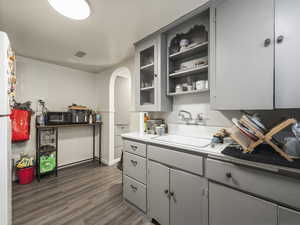 Kitchen with gray cabinets, sink, and dark wood-type flooring